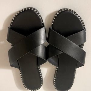 Black flat open toe sandals with silver stitched lining.